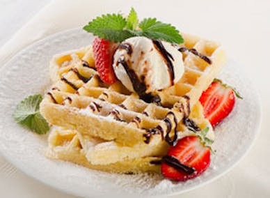 Våffeljärn för belgiska våfflor. Belgisk våffla som serveras med glass, chokladsås och färska jordgubbar.